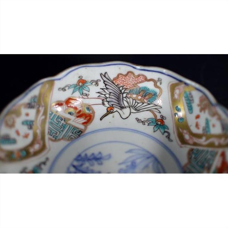 Close-up of antique hand painted Japanese Imari porcelain bowl with crane and red, teal, and gold floral designs.