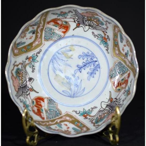 Red, blue, and gold hand-painted Japanese Imari porcelain bowl with crane and floral designs on brass stand.