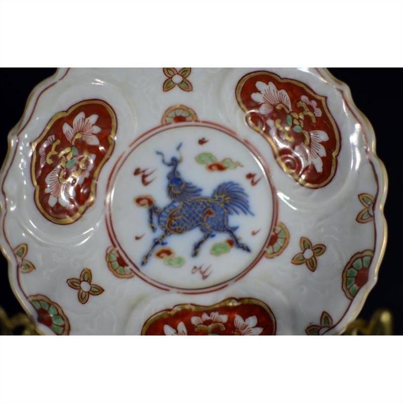 Close-up of antique hand painted Japanese Imari porcelain plate with floral patterns and blue mythical creature centerpiece.