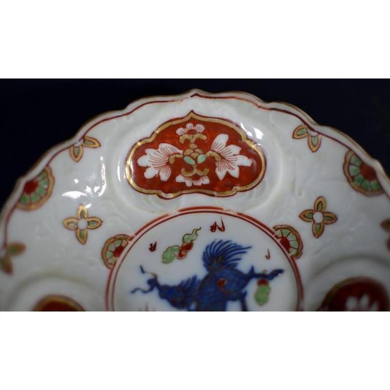 Close-up of an antique Japanese Imari porcelain plate with red, white, blue, and green floral and bird designs.