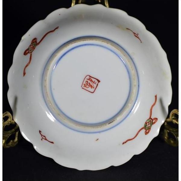 Close-up of an antique hand painted Japanese Imari porcelain plate with red and green designs on white background.