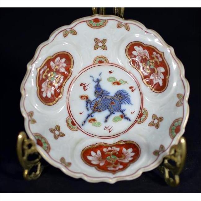 Close-up of blue and red hand painted Imari porcelain plate with gold rim and mythical animal motif.