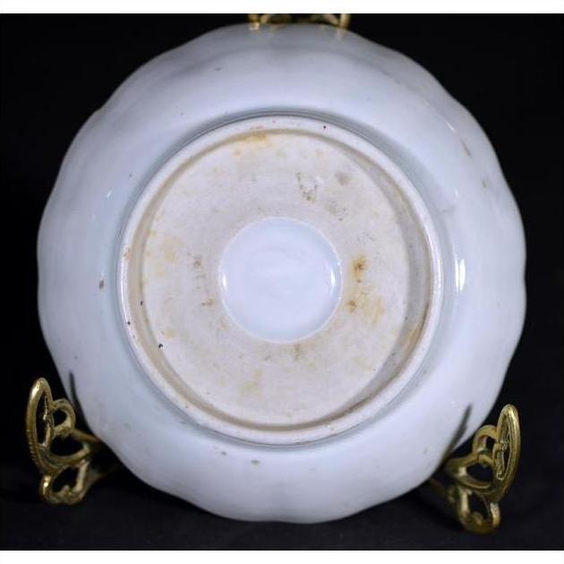 Close-up of the underside of an antique hand painted Japanese Imari porcelain plate with stains on a gold stand.