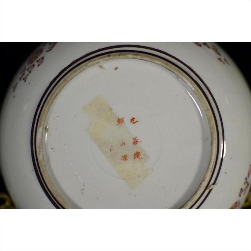 Close-up of the bottom of a Kutani porcelain bowl with red marks, tape, and visible antique hand painted details.