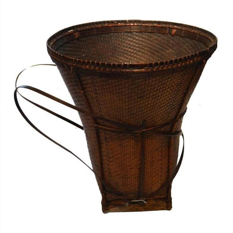 Brown rattan cone-shaped basket with two back straps, plain background.