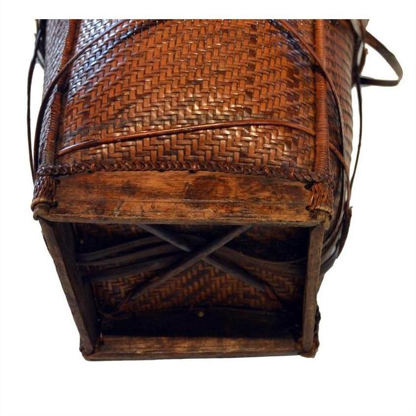 Close-up of brown rattan and wood basket bottom with intricate wicker pattern.