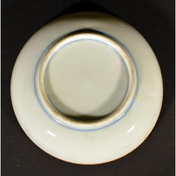 Close-up of the base of a round white ceramic Antique Igezara Transferware plate against a dark background.