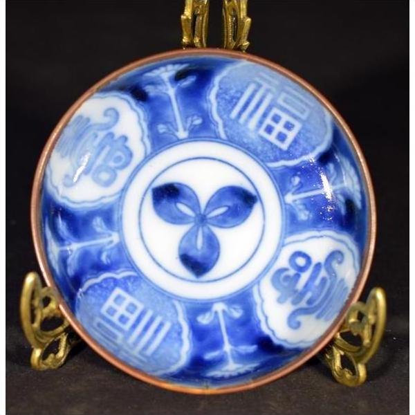 White porcelain Igezara transferware plate with blue floral and geometric patterns on a decorative gold stand.