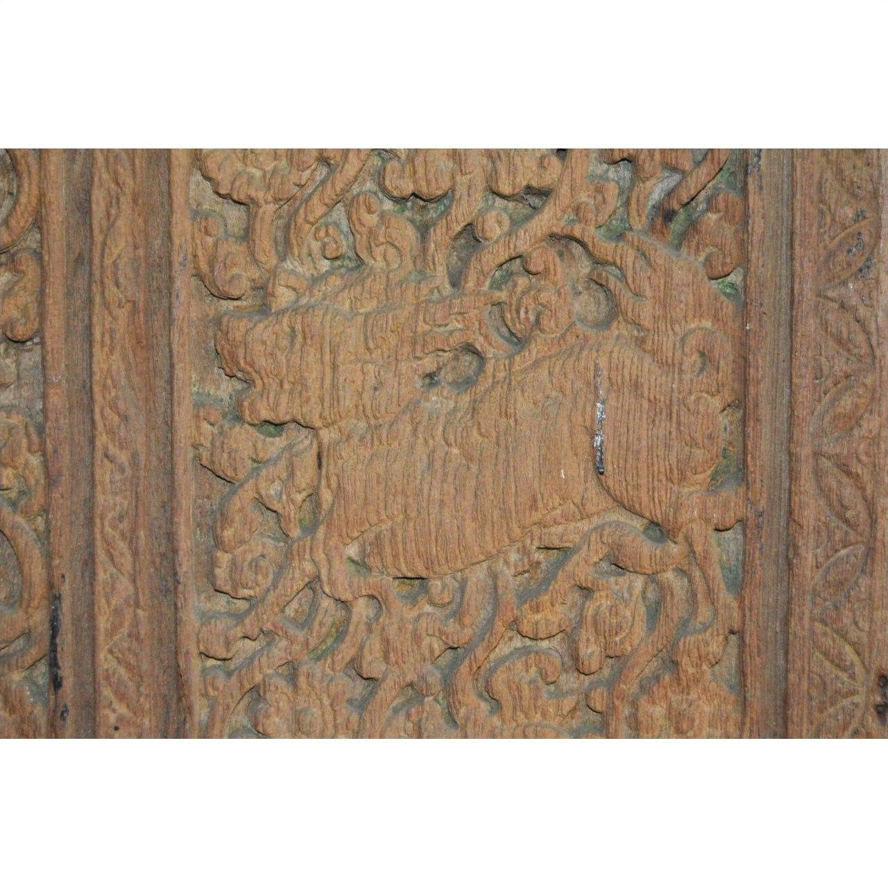 Brown wooden antique Indian door with detailed lion carving and ornate floral patterns, close-up view.