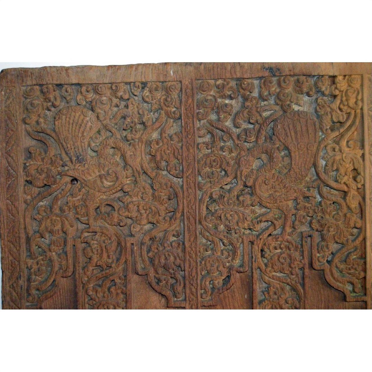 Brown Sheesham wood antique door with carved stylized birds, floral and vine patterns.