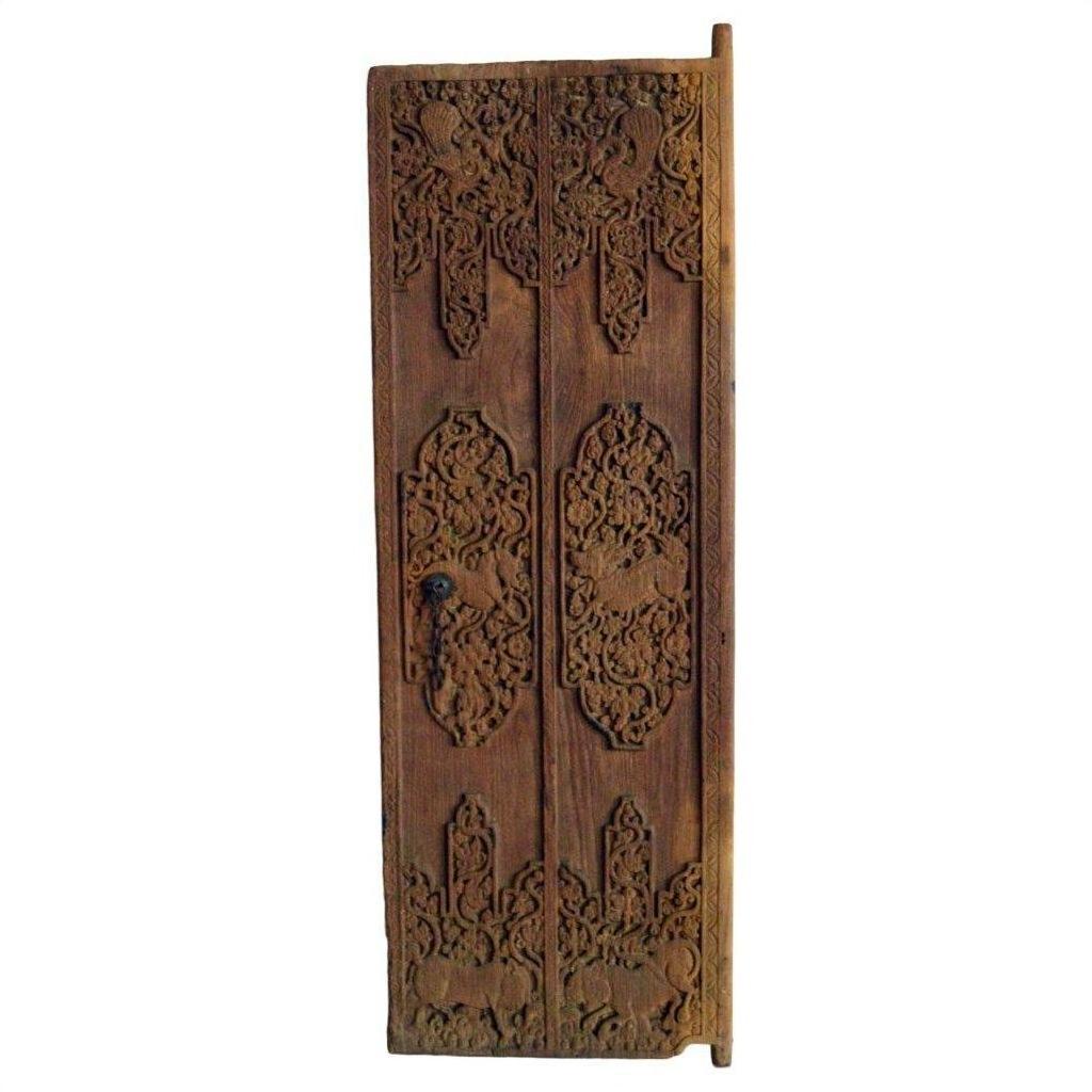 Tall narrow brown Sheesham wood Indian door with carved floral and geometric patterns, iron hardware visible.
