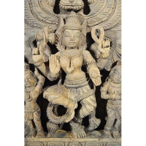 Brown sheesham wood hand-carved temple decoration with ornate multi-armed Hindu deity, close-up view.