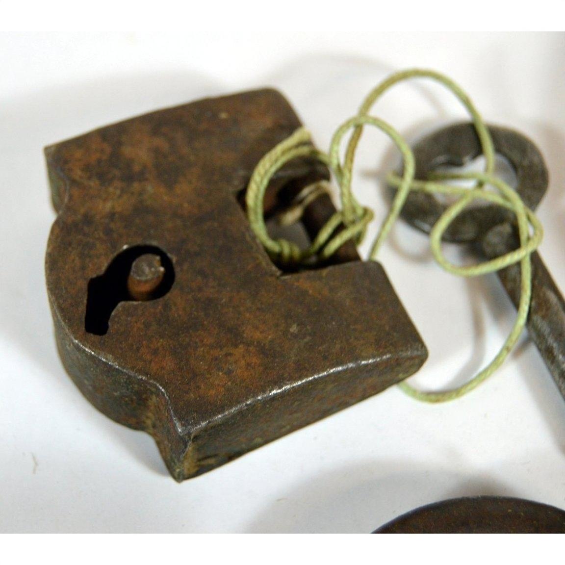 Close-up of antique Indian brass locks with original key tied by string on a white background.