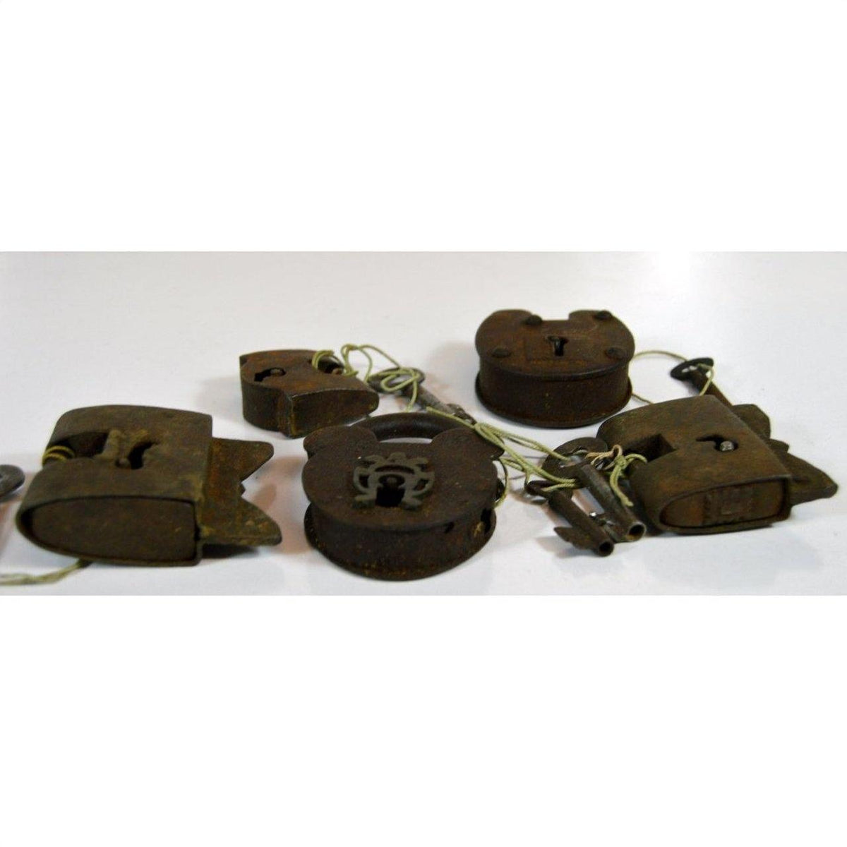 Brass and iron antique Indian locks with original keys on a white surface.