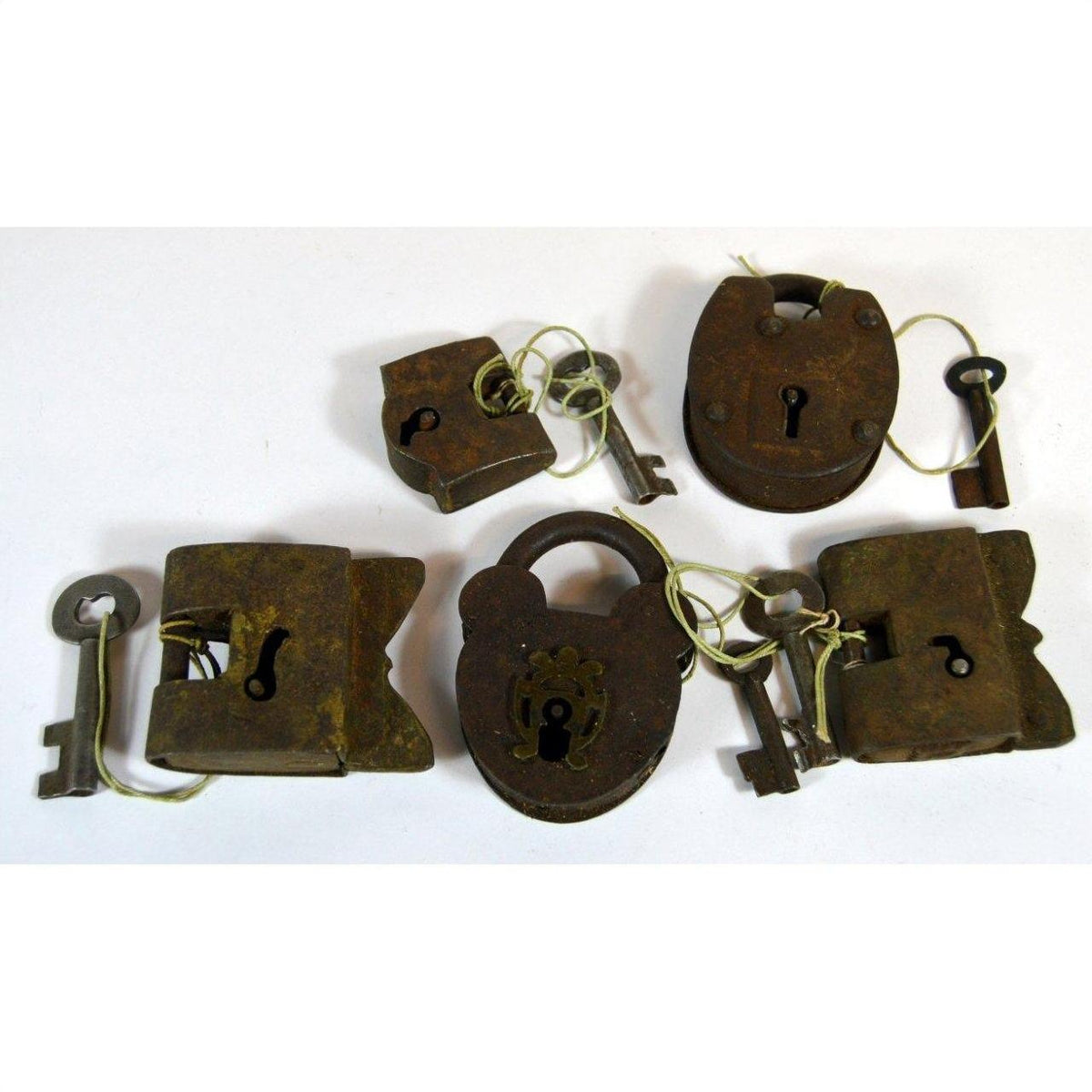 Close-up of five antique brass Indian locks with original keys displayed on a white background.