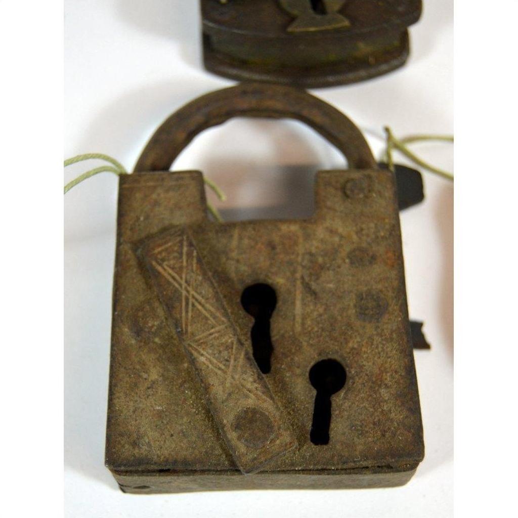 Antique metal Indian lock with two keyholes and engraved patterns on a white background.