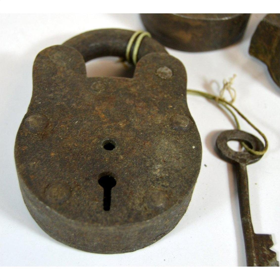Close-up of antique brass Indian locks and a key tied with string on a white background.