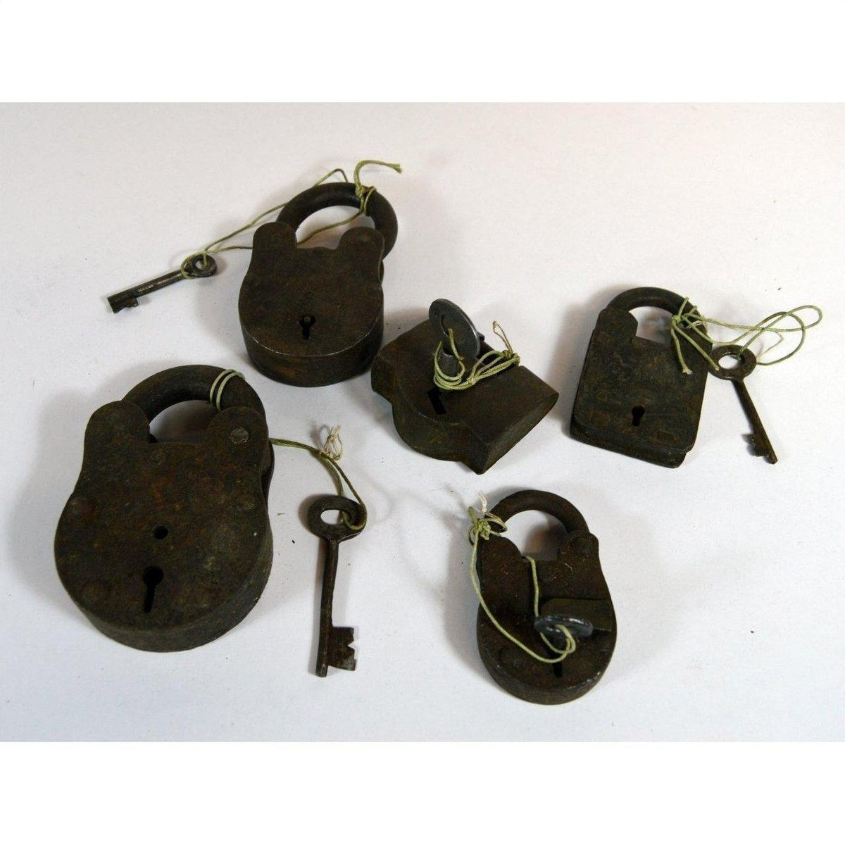 Antique brass Indian locks with matching keys, tied with string, displayed on a white surface.