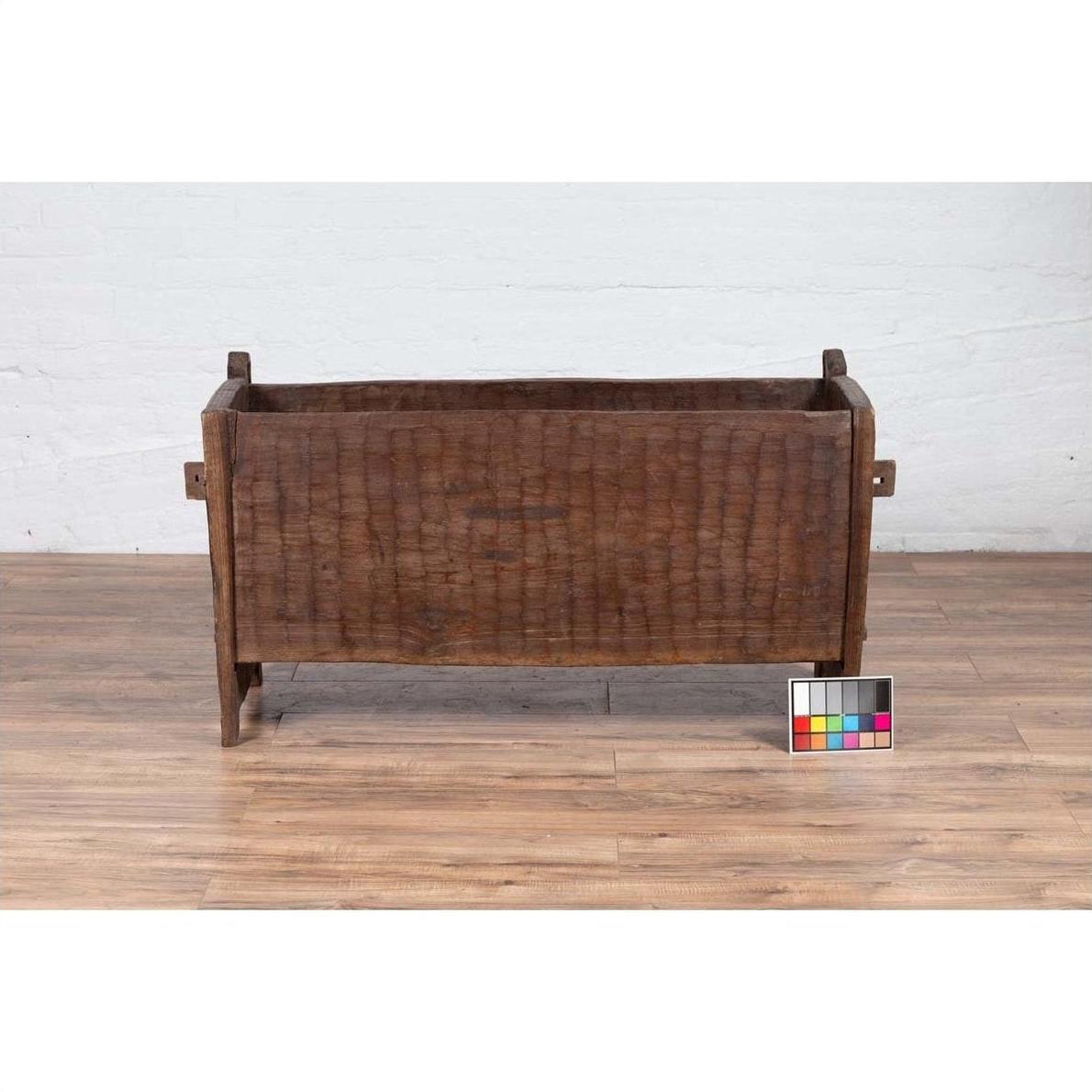 Brown weathered wooden planter on a wooden floor with a color chart in front.
