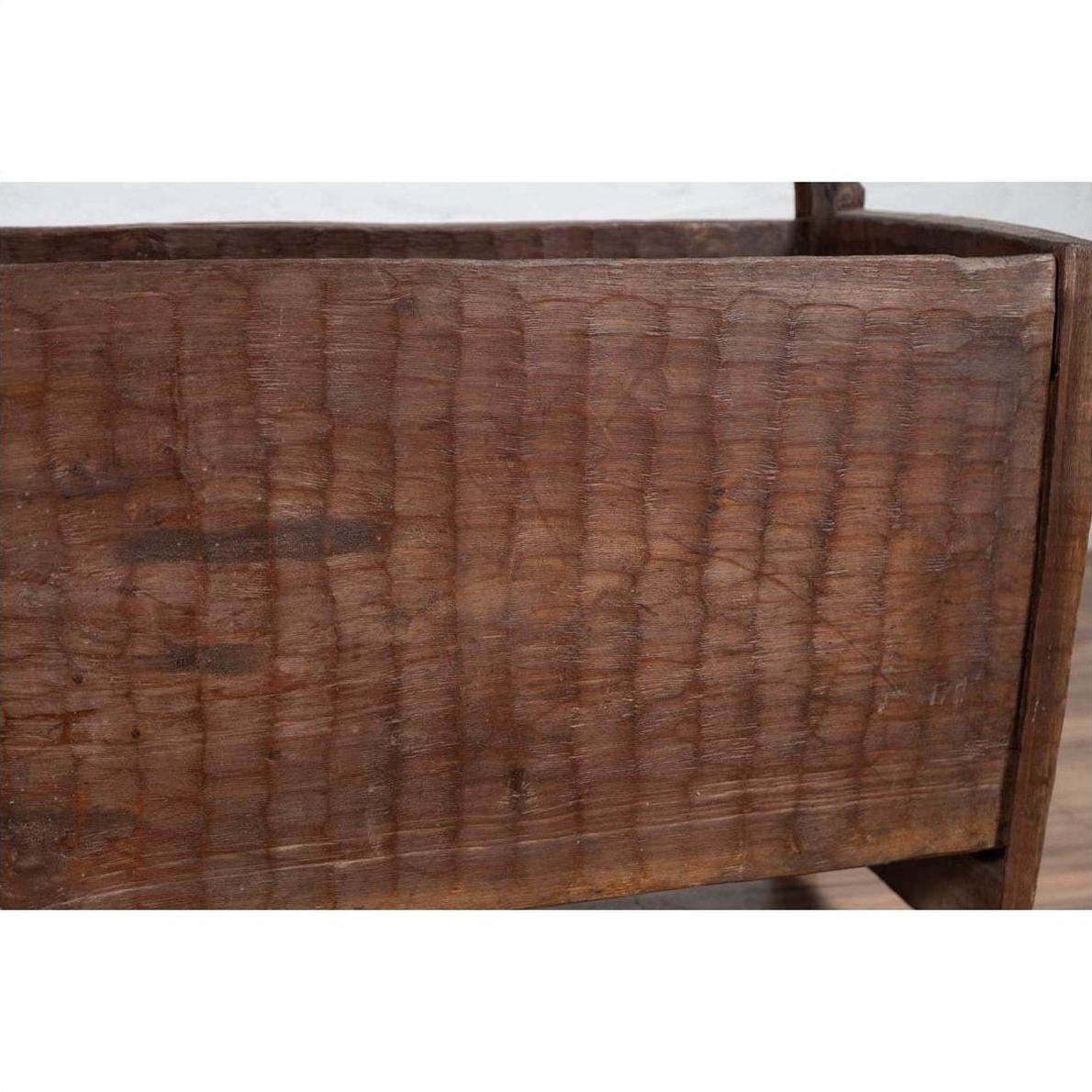 Brown wood planter close-up with weathered, chiseled finish and visible grain.