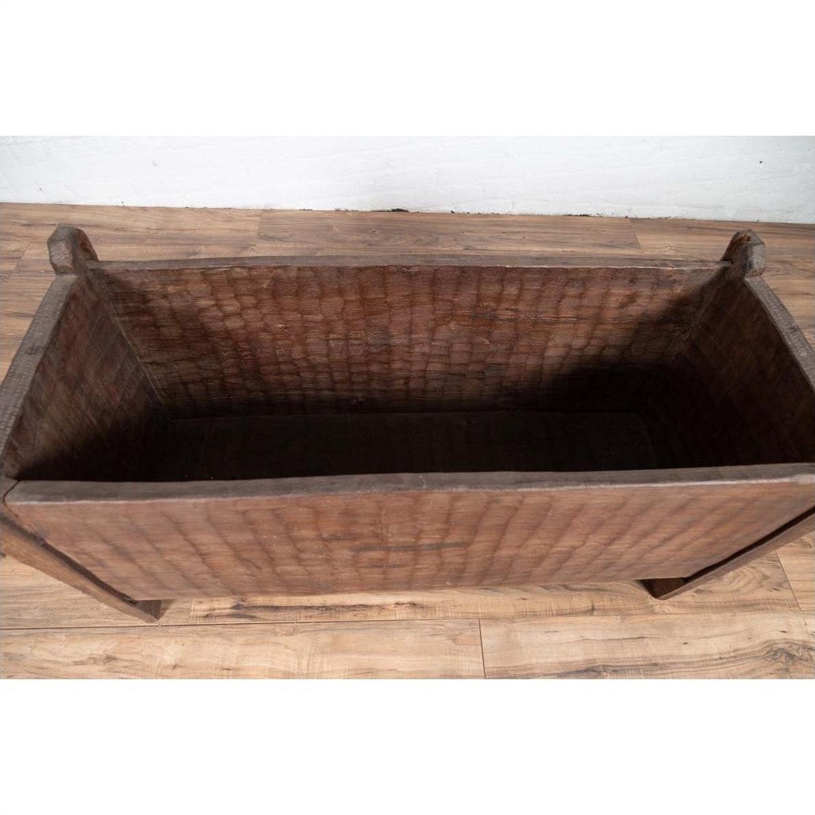 Brown weathered wood rectangular planter with side handles, on wooden floor against a white wall indoors.