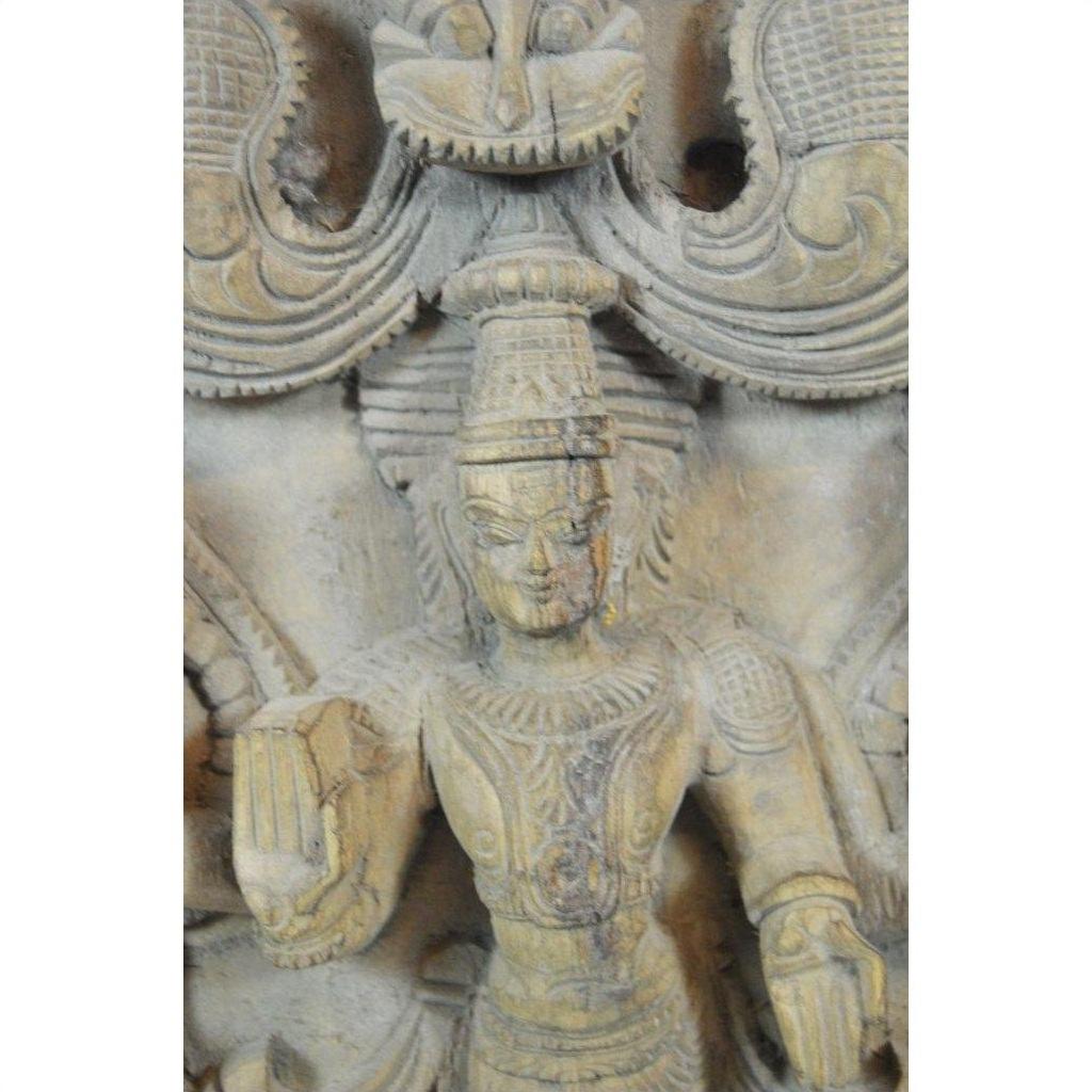 Brown sheesham wood carving of Shiva holding a book, ornate headdress and jewelry, detailed Indian design.