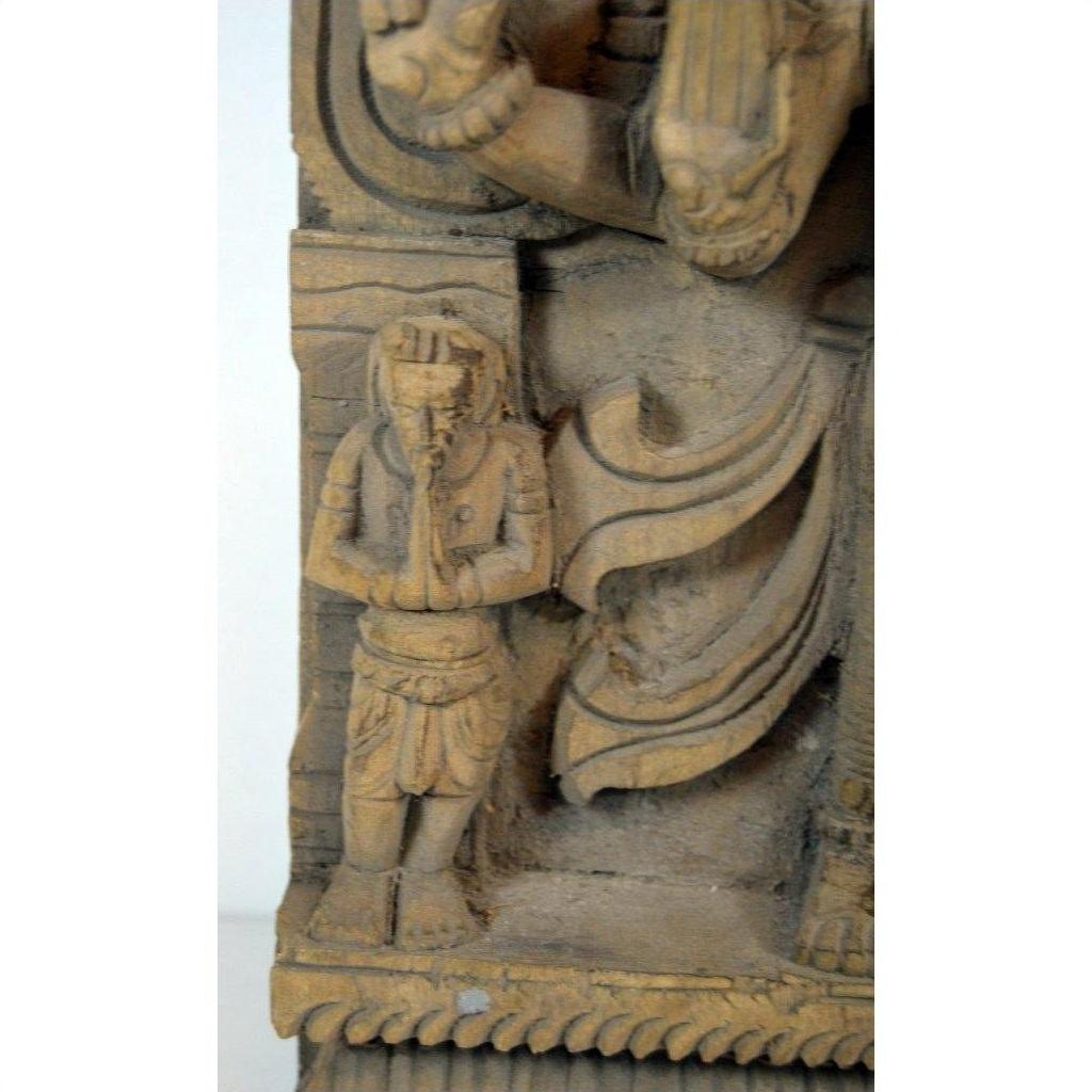 Brown Sheesham wood carving of small praying figure beside larger draped figure, Indian antique style, close-up.