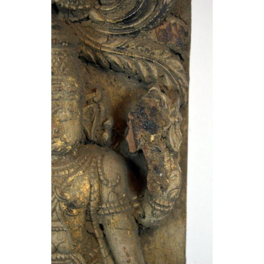 Close-up of brown Sheesham wood carving, antique Indian art with weathered torso and raised hand detail.