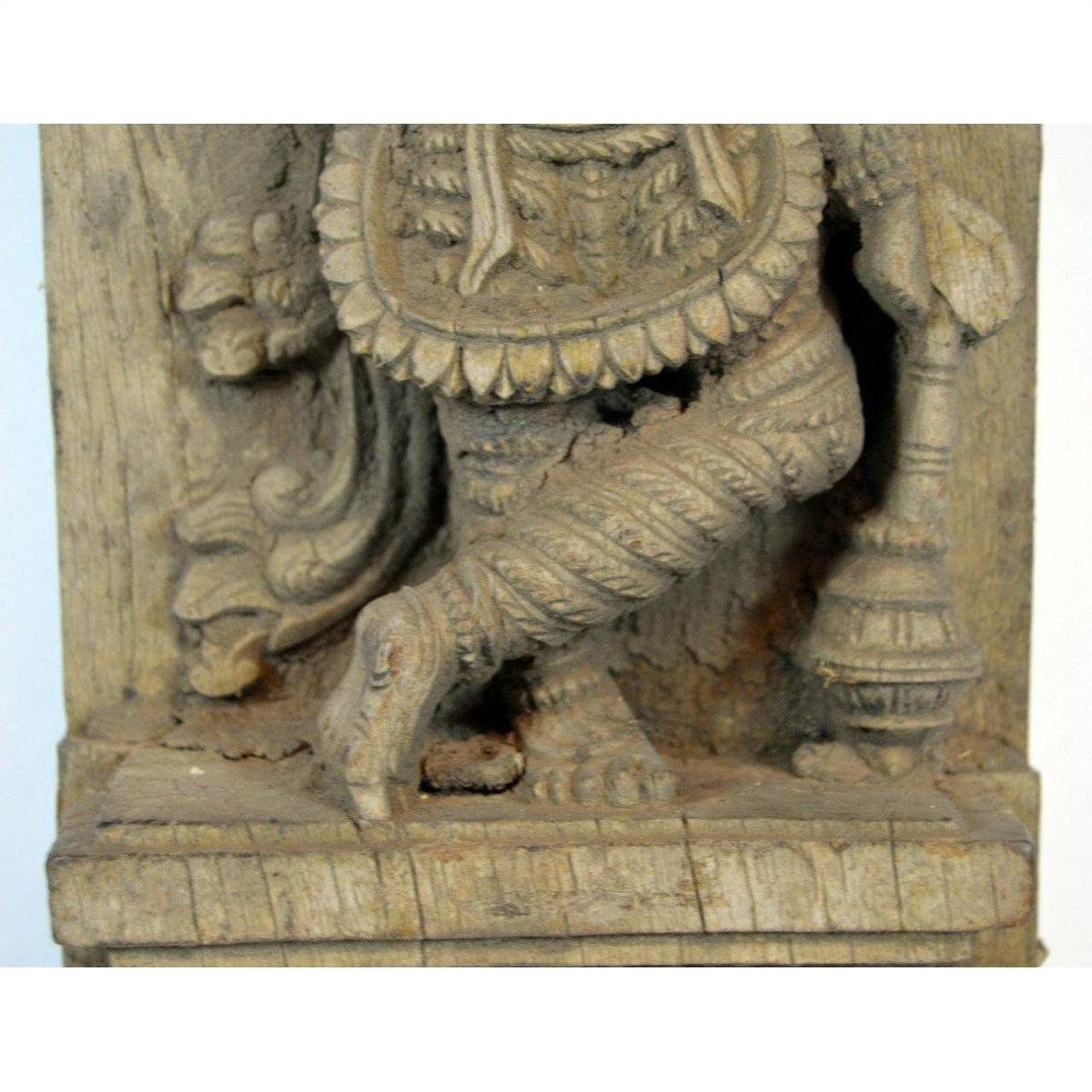 Close-up of brown Sheesham wood carved lower legs and feet in intricate antique Indian attire.