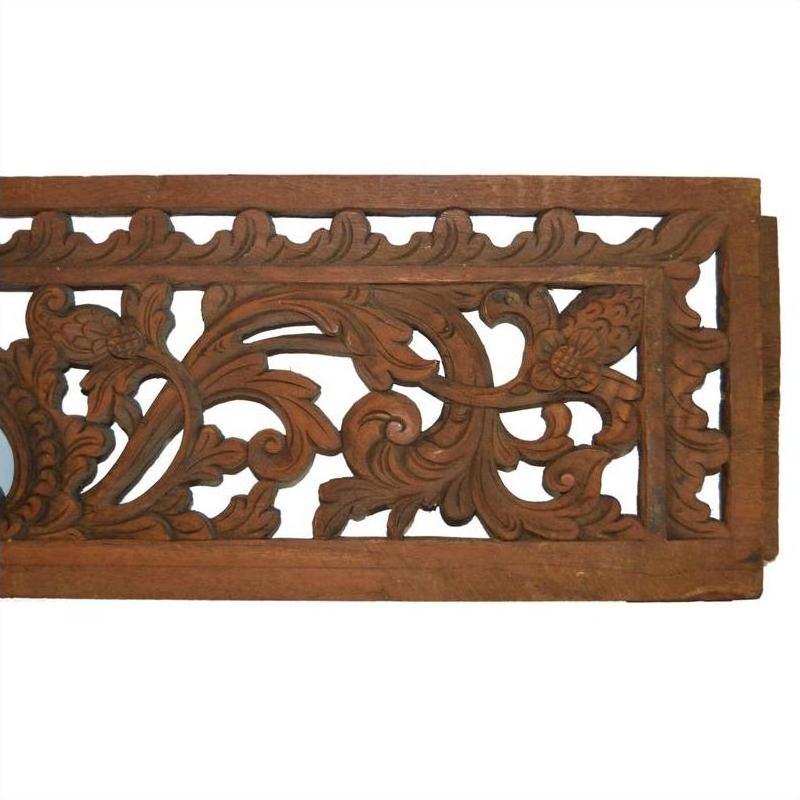 Brown wooden Indonesian carving with intricate floral and leaf patterns, close-up view, suitable for wall décor.