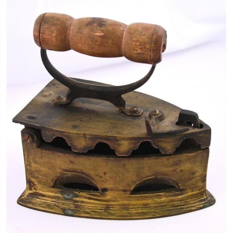 Close-up of antique Indonesian coal iron with brown wooden handle, metal body, vent holes, and compartment.