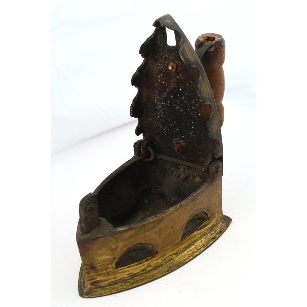 Close-up of antique Indonesian coal iron with rusted metal lid and wooden handle, vintage look.