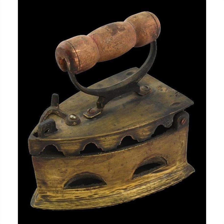 Brass coal iron with wood handle, vent holes, and latched lid on display as vintage décor.