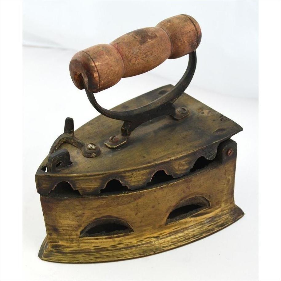 Close-up of antique Indonesian coal iron with wooden handle and vent holes, dark metal finish, vintage style.