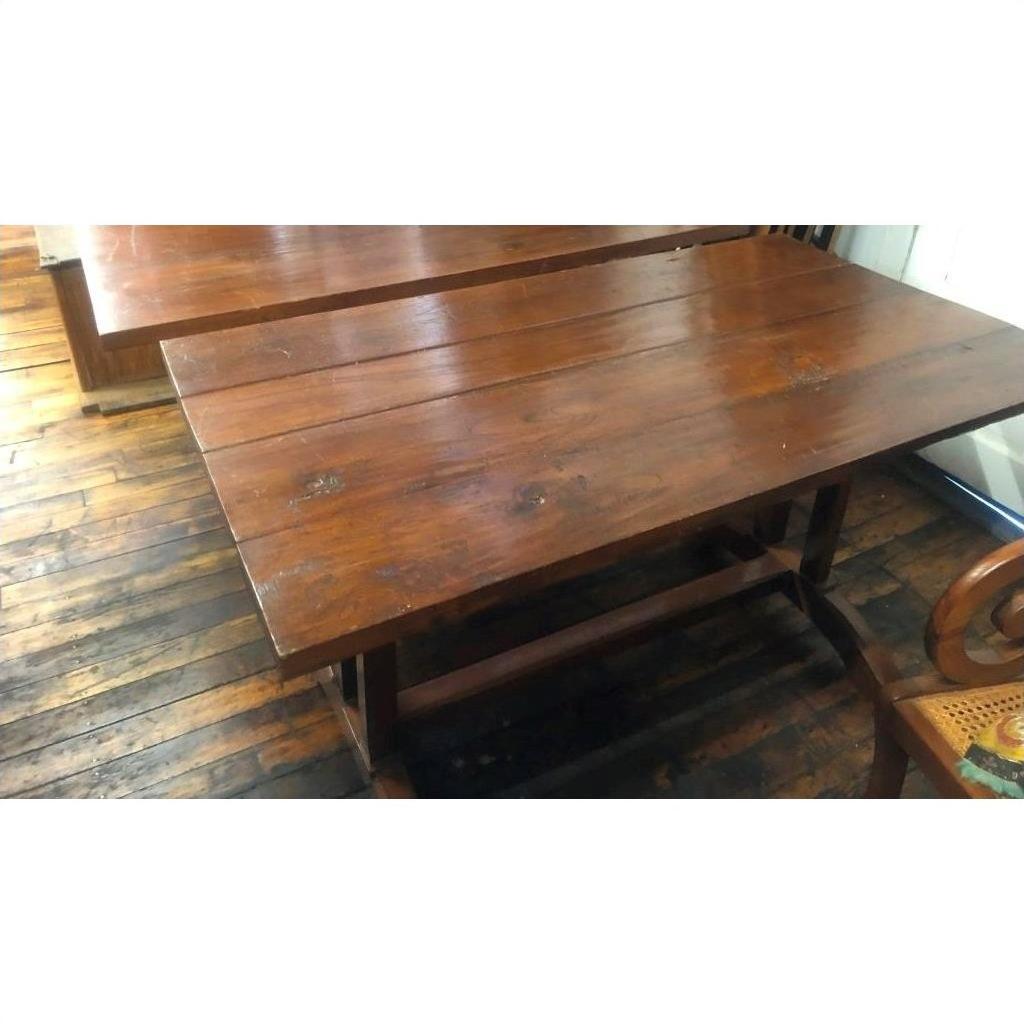 Brown wood antique Indonesian dining table with plank top and sturdy legs, beside matching chair on wooden floor.