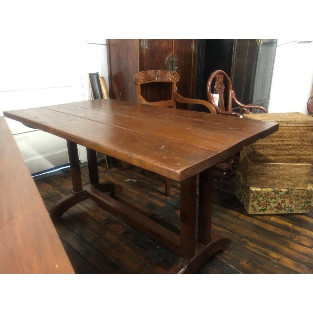 Brown wood antique Indonesian dining table on rustic floor, surrounded by vintage furniture and matching chair.