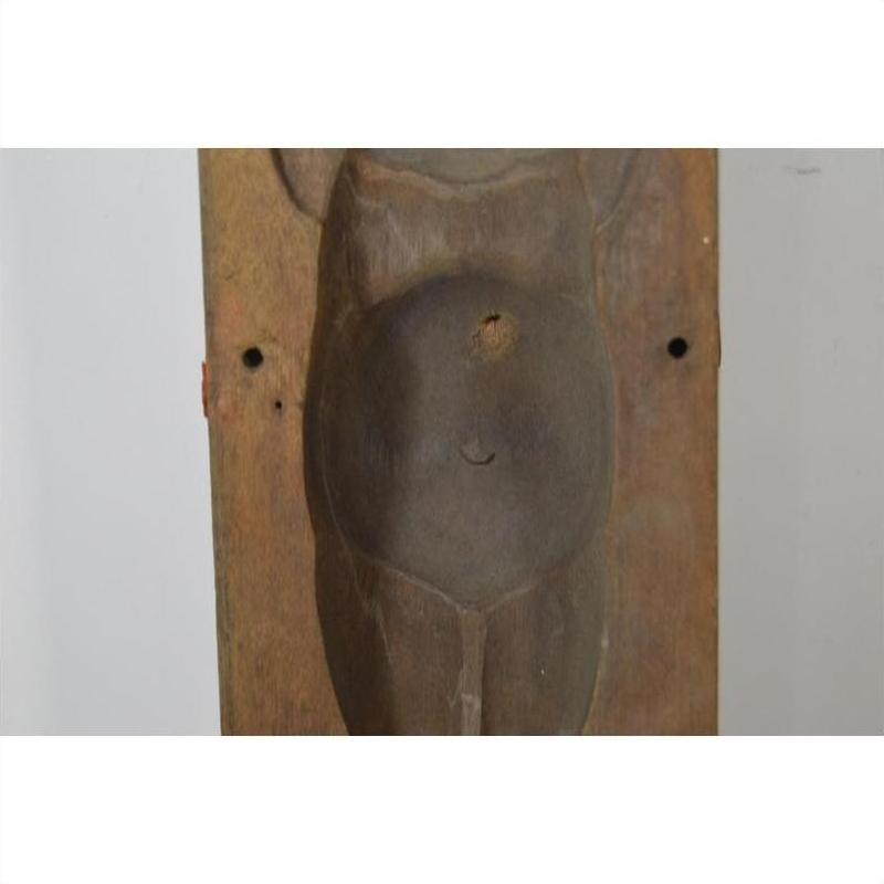 Brown wooden Indonesian mold, hand carved with torso, rounded belly, and small navel hole, close-up on neutral background.