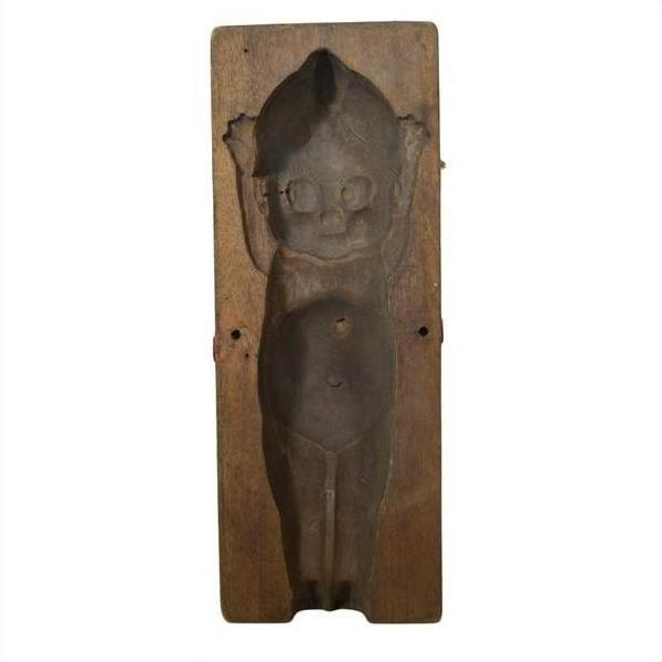 Brown wooden hand-carved Indonesian mold, doll design with raised arms and detailed face, close-up view.