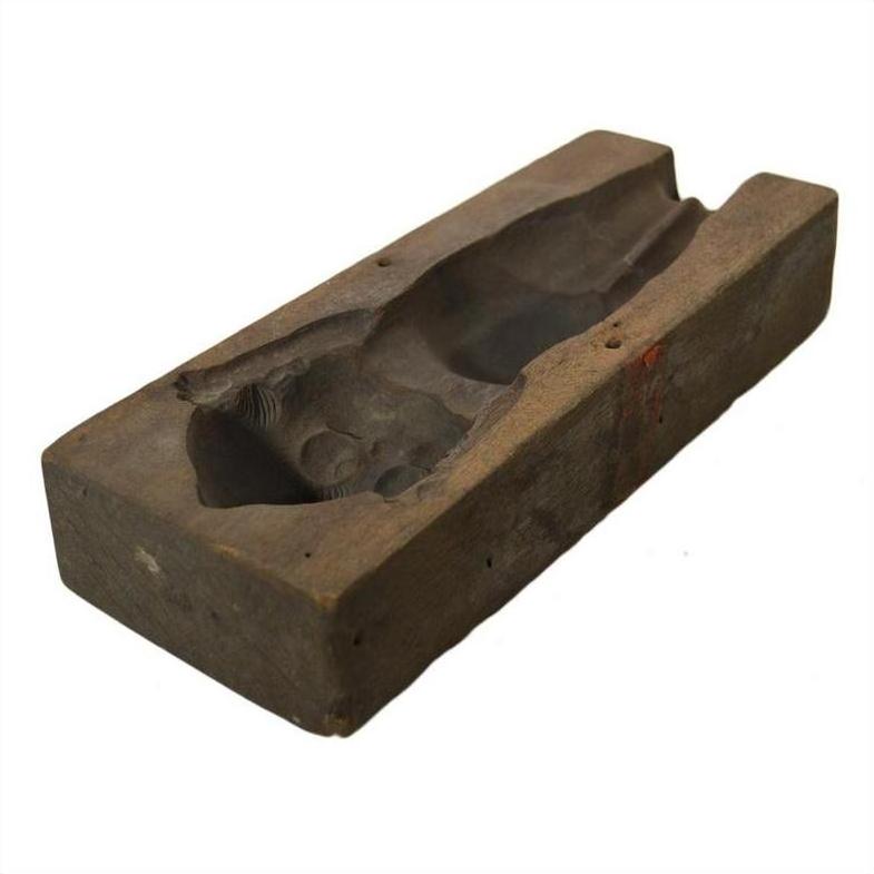 Brown wooden hand-carved Indonesian mold with carved cavity, likely used for casting or shaping objects, on plain background.