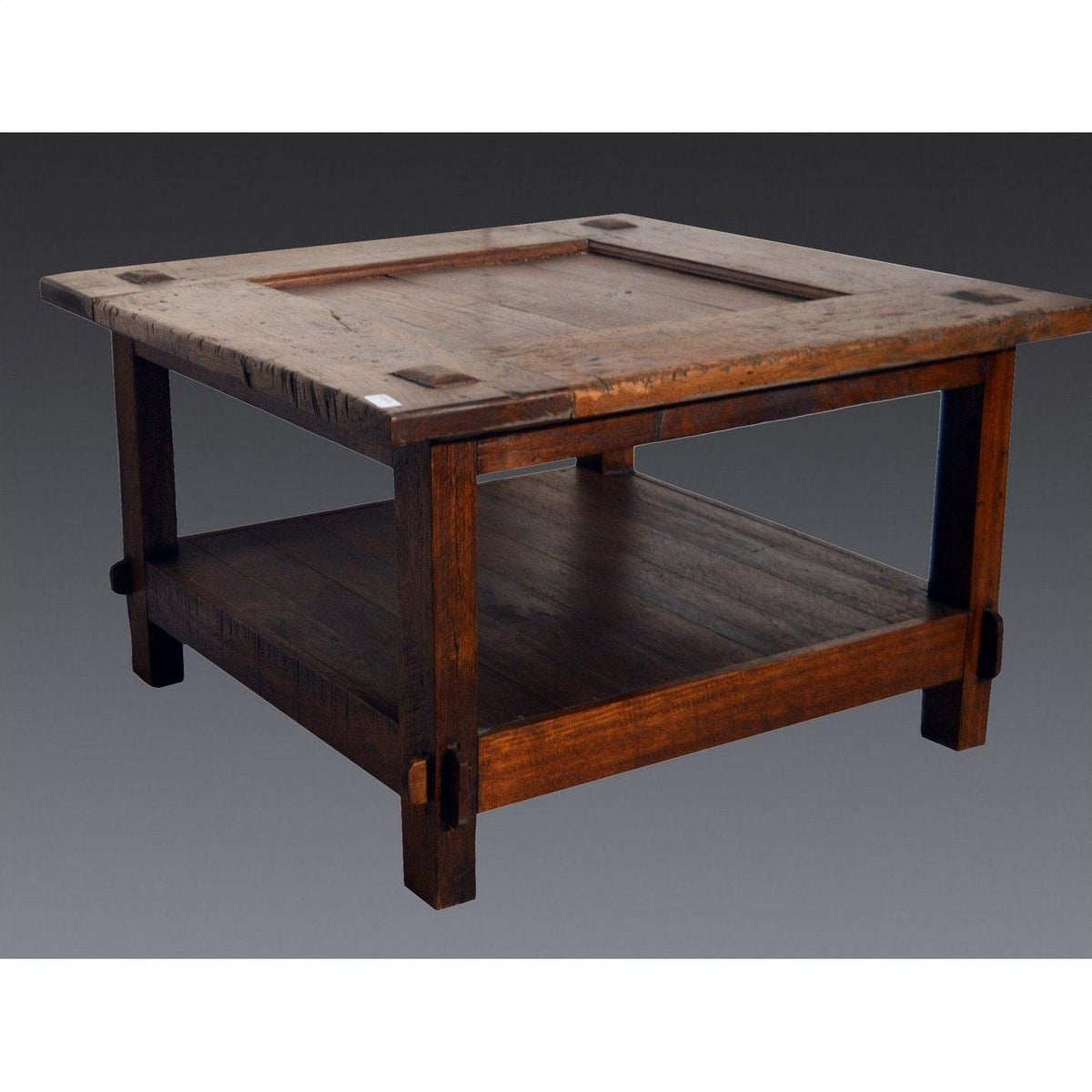 Brown wooden Indonesian coffee table with lower shelf, Dutch Colonial style, on plain background.