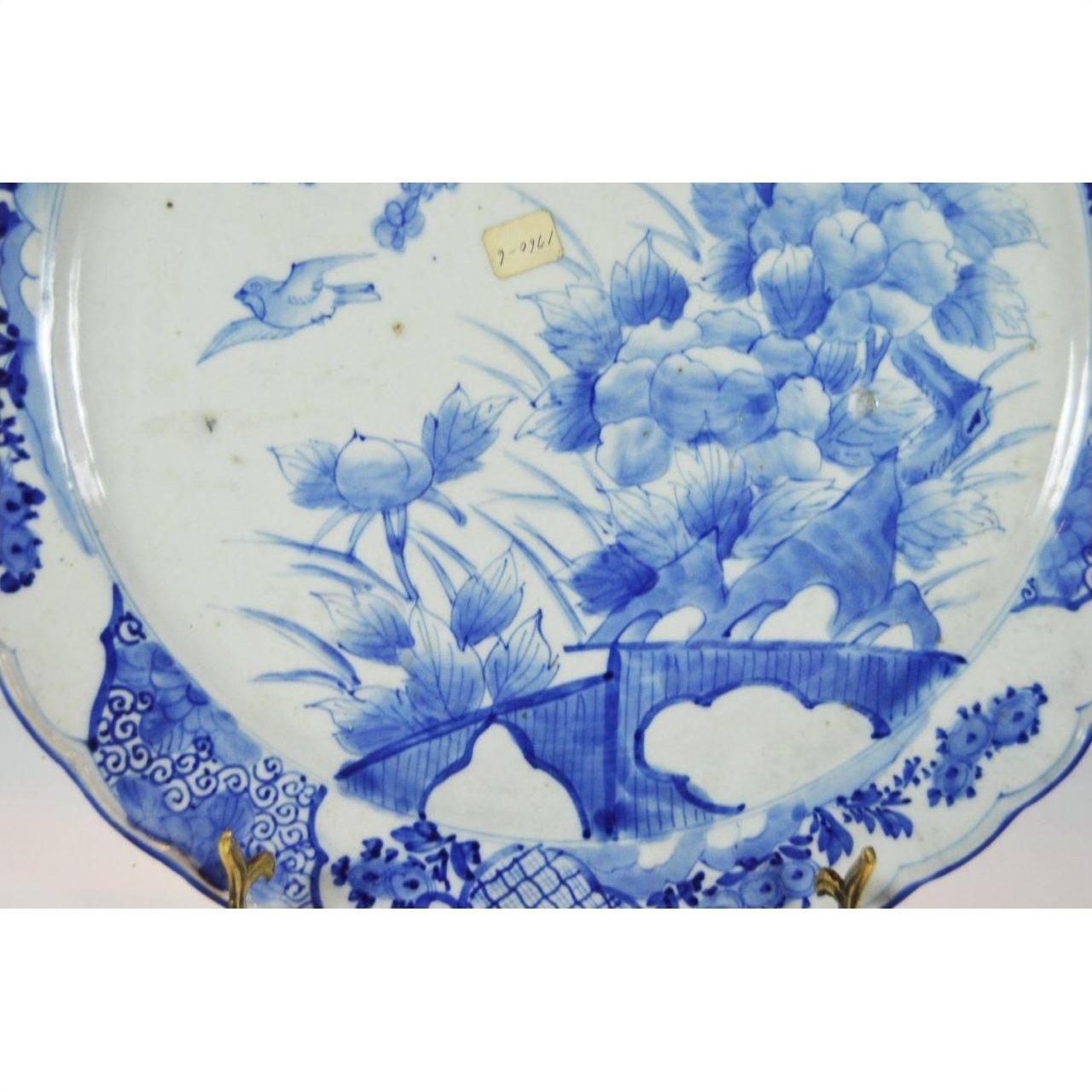 Close-up of blue and white porcelain Japanese hand painted plate with floral and bird design, small price sticker visible.