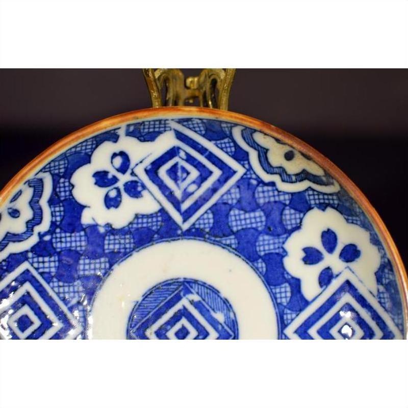 Blue and white ceramic Igezara transferware plate with geometric and floral patterns displayed on a metal stand.