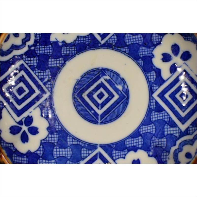Blue and white ceramic Igezara transferware plate with geometric diamond and floral motifs, close-up.