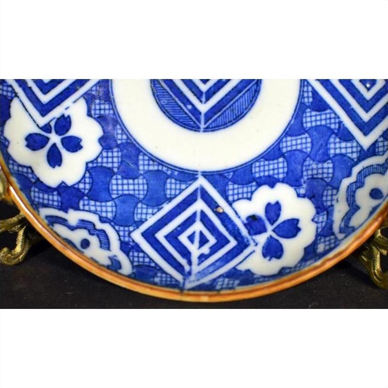 Blue and white ceramic Igezara transferware plate with geometric and floral patterns on a brass stand.