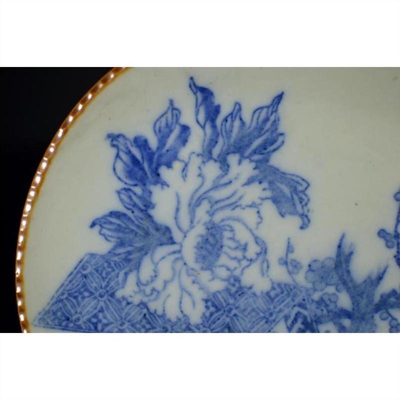 Close-up of blue and white ceramic Igezara Japanese transferware plate with floral design and gold-trimmed edge.