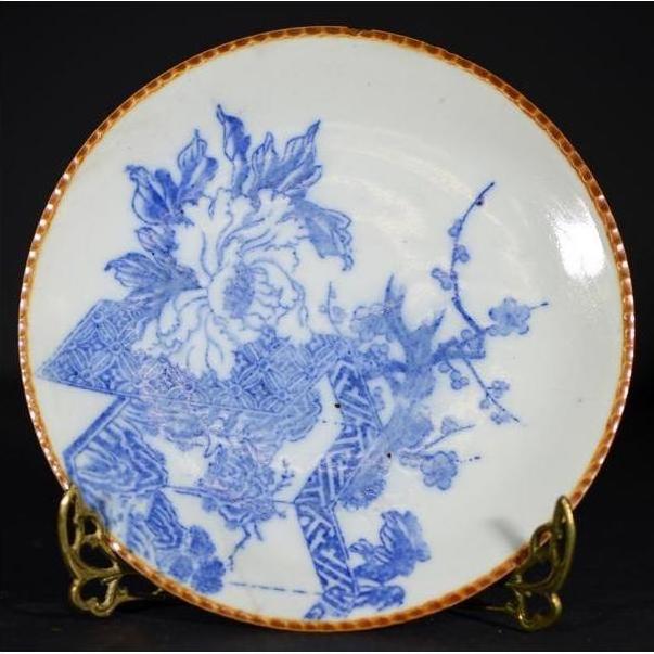 Blue and white ceramic Igezara transferware plate with floral and geometric designs, brown rim, on brass stand.
