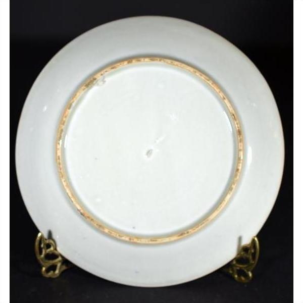 Close-up of the back of an antique Japanese Igezara transferware plate with gold rim on a metal stand.