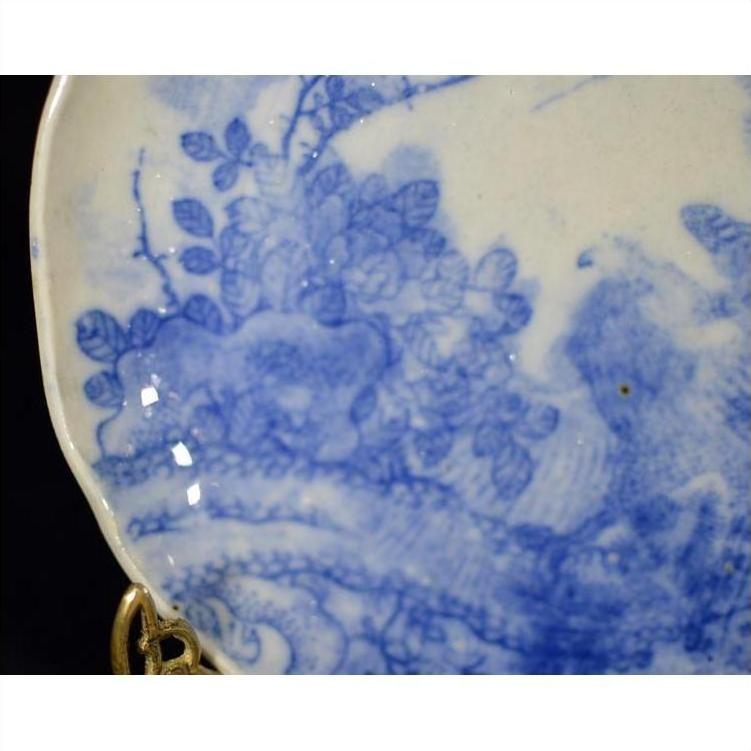 Close-up of blue porcelain Japanese Igezara transferware plate with floral pattern in gold plate holder.