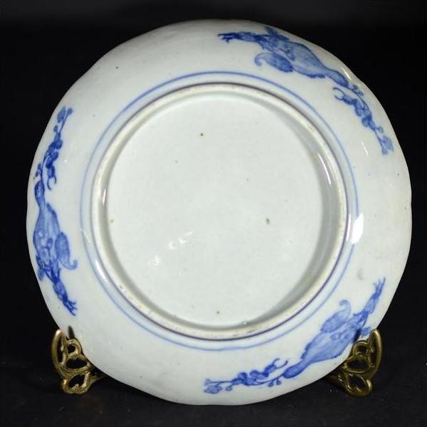 Close-up of the underside of an antique Japanese Igezara transferware plate on a metal stand.