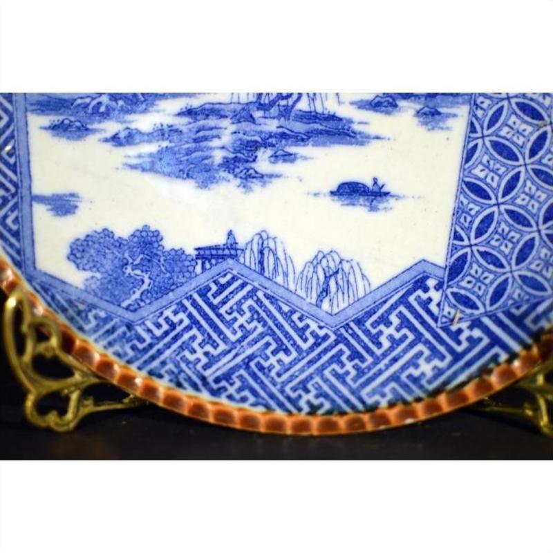 Close-up of a blue and white ceramic Japanese Igezara transferware plate with intricate patterns, on a display stand.